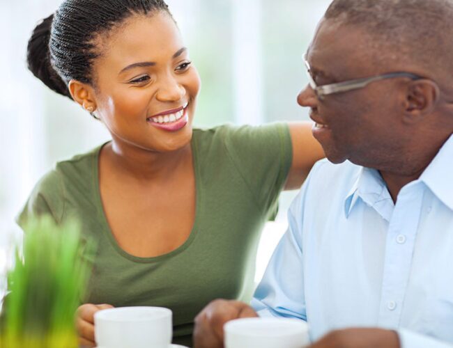 A man and woman smiling at each other drinking from mugs