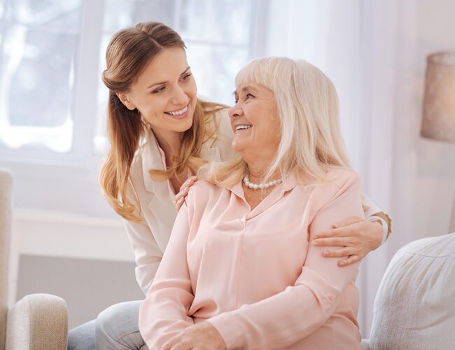 adult daughter hugging and smiling at her senior mother