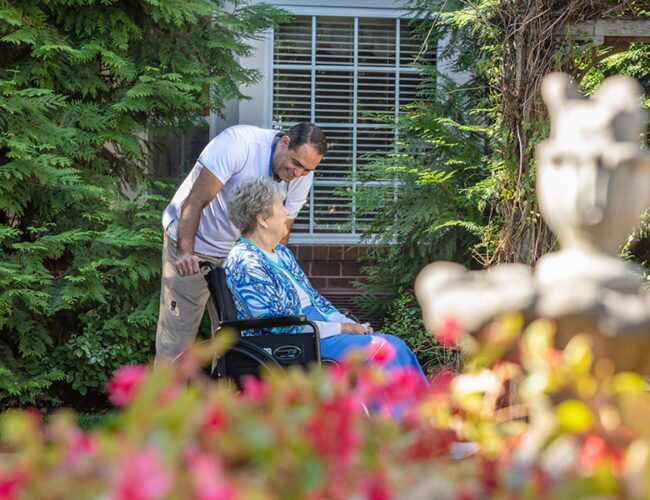Man in purple pushing woman wearing blue in a wheelchair