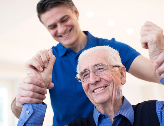 younger man holding a senior man's hands up while smiling