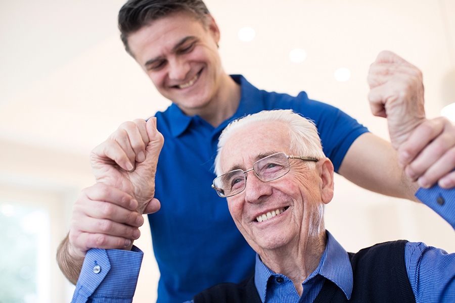 younger man holding a senior man's hands up while smiling