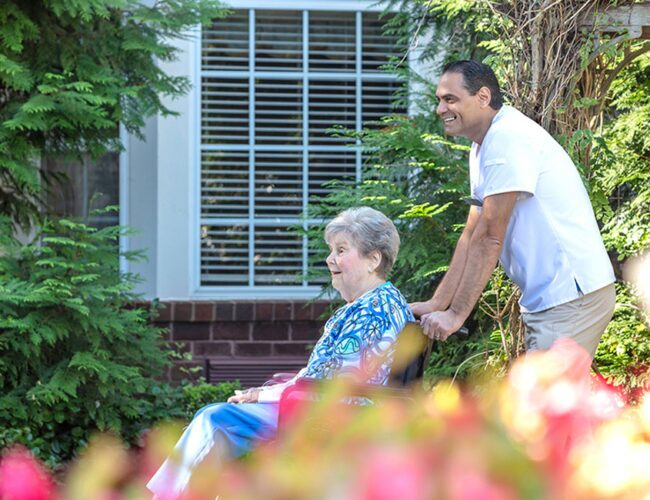 nurse pushing a senior woman in a wheelchair outside