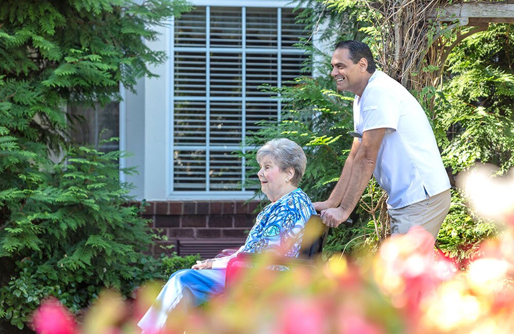 nurse pushing a senior woman in a wheelchair outside