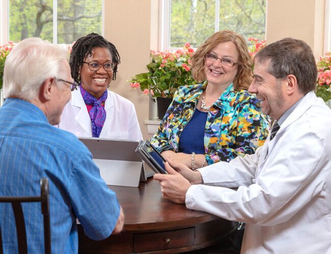 Medical experts in dementia consulting with a memory care resident.