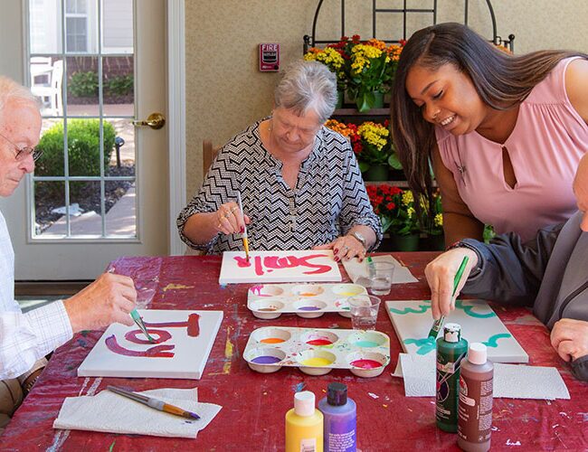 A caregiver paints with residents.