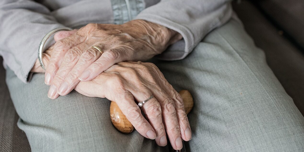 senior hands crossed over each other on a cane