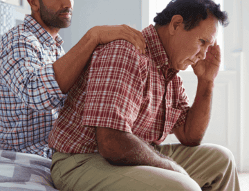 adult son consoling senior father