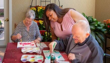Parc Provence activities coordinator guiding residents in a painting exercise.