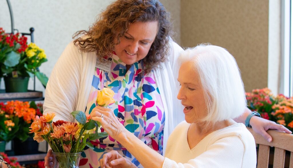 Activity Director with female resident doing a flower arrangement.
