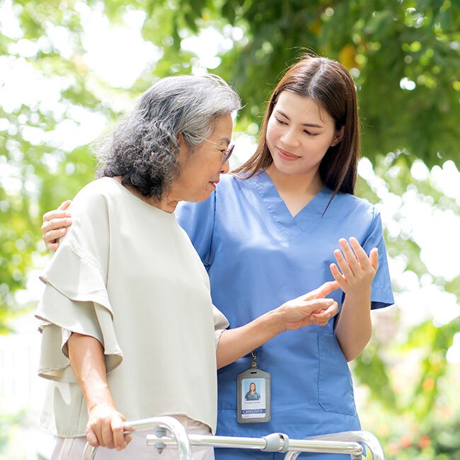 A caregiver walks with a resident outdoors.