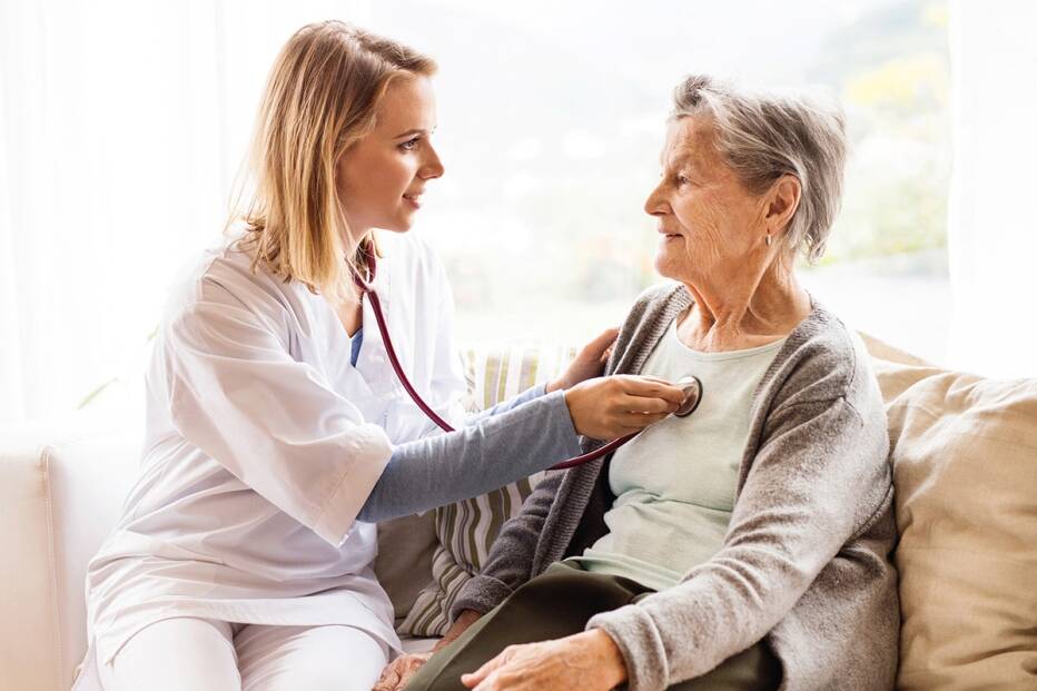 doctor taking a senior woman's heart rate with a stethoscope