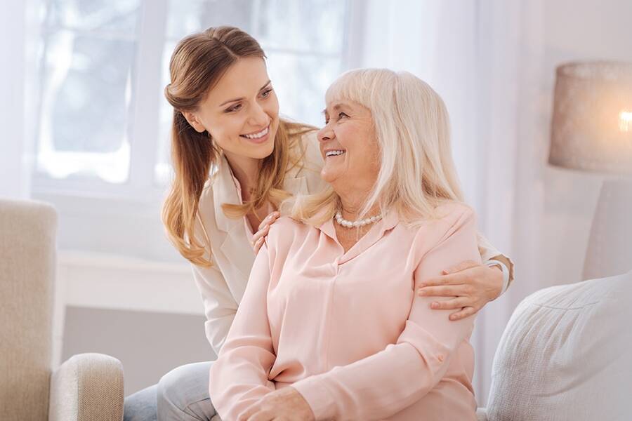 adult daughter hugging and smiling at her senior mother