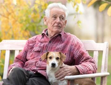 Man sitting on bench outside with a dog