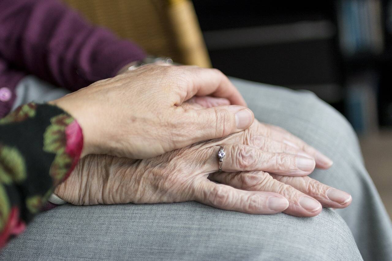 close-up of two people's hands - one comforting the other's.