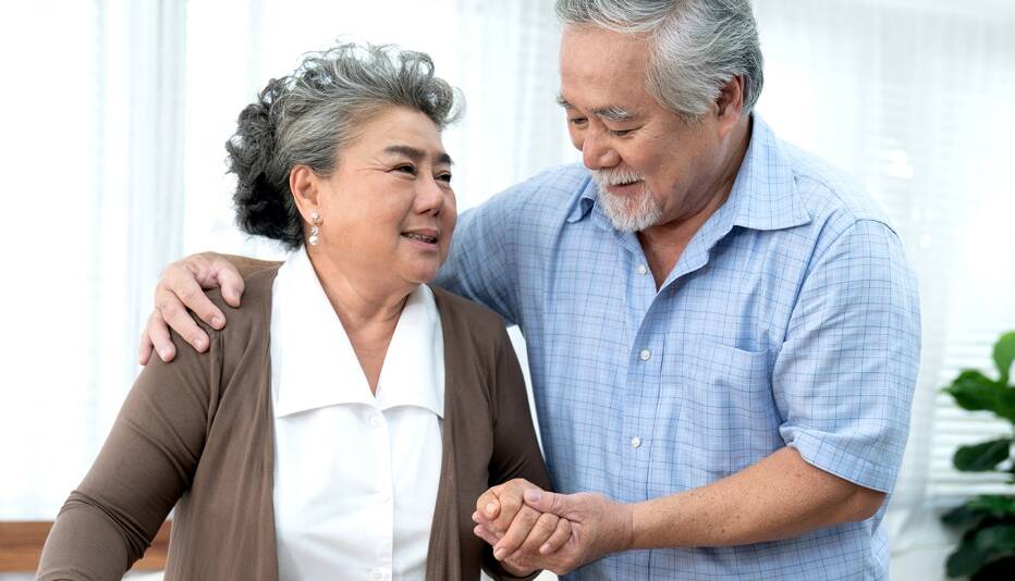 senior couple holding each other with senior man's arm around the woman