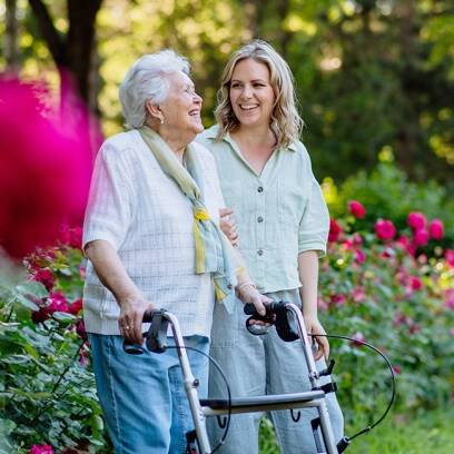 A caregiver walks with a resident outdoors.