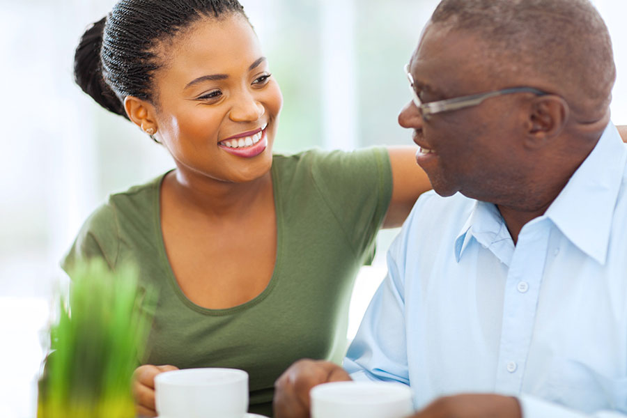 A man and woman smiling at each other drinking from mugs