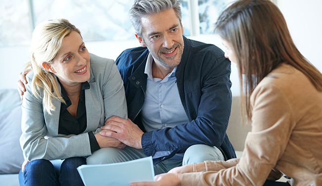 Three adults smiling and having a conversation