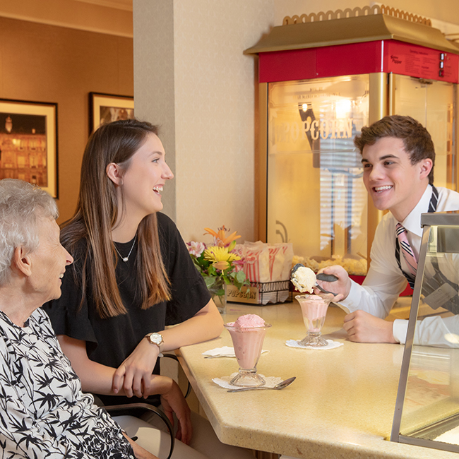 A young woman and an older woman enjoying a drink with a male service worker