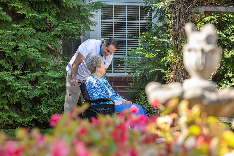 Man in purple pushing woman wearing blue in a wheelchair