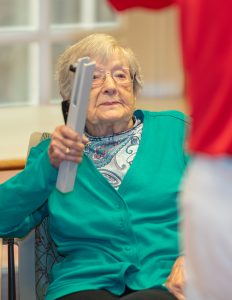 Resident in teal cardigan plays a wind chime