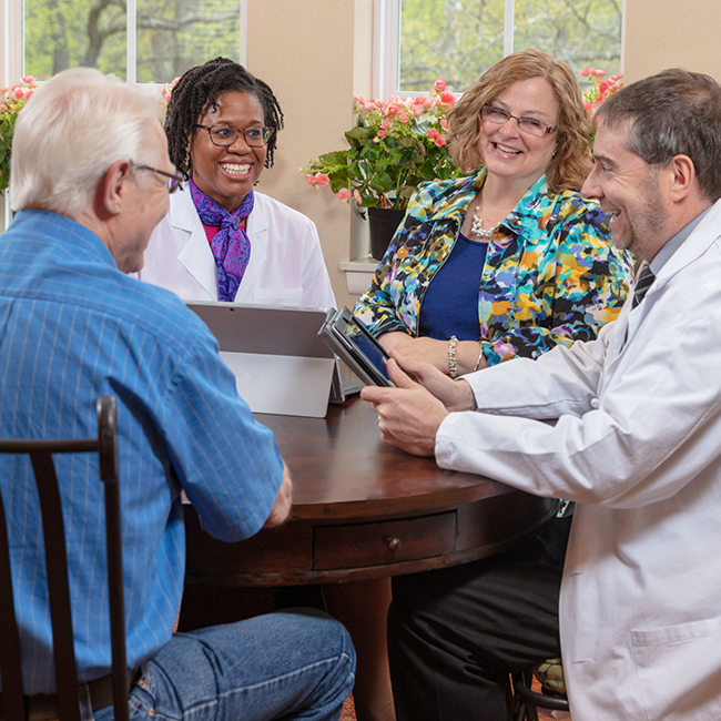 Group of adults sitting around a wooden table smiling