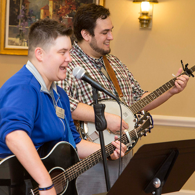 Two musicians playing a guitar and a banjo while singing into a microphone