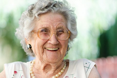 Senior woman sitting outside and laughing.