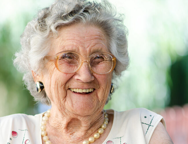 Senior woman sitting outside and laughing.