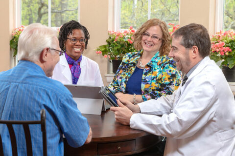Medical experts in dementia consulting with a memory care resident.