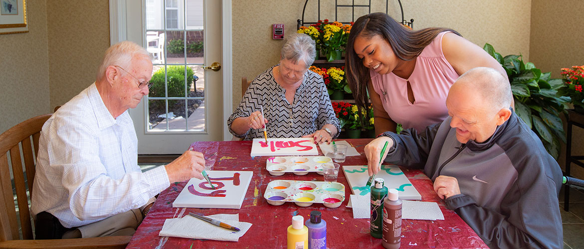 A caregiver paints with residents.