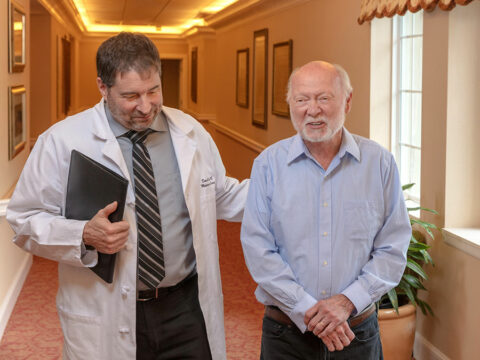 A doctor walks down the hallway with a resident.