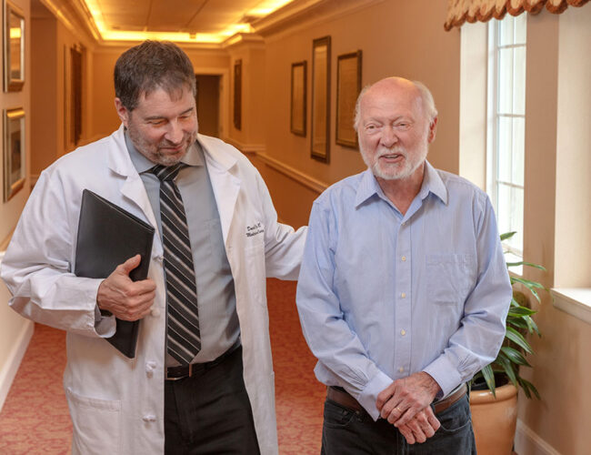 A doctor walks down the hallway with a resident.