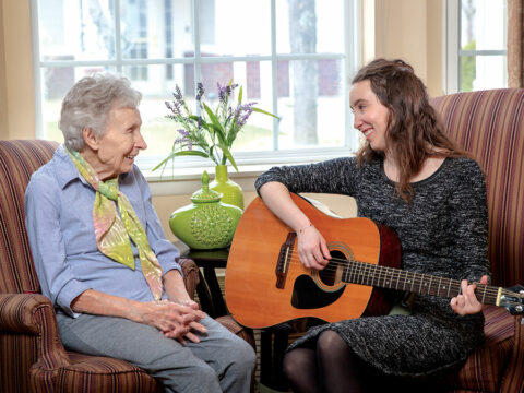 A caregiver playing the guitar for a resident.