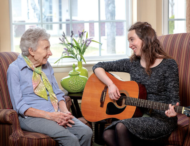 A caregiver playing the guitar for a resident.