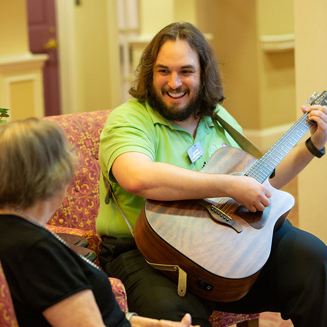 A caregiver playing the guitar for a resident.