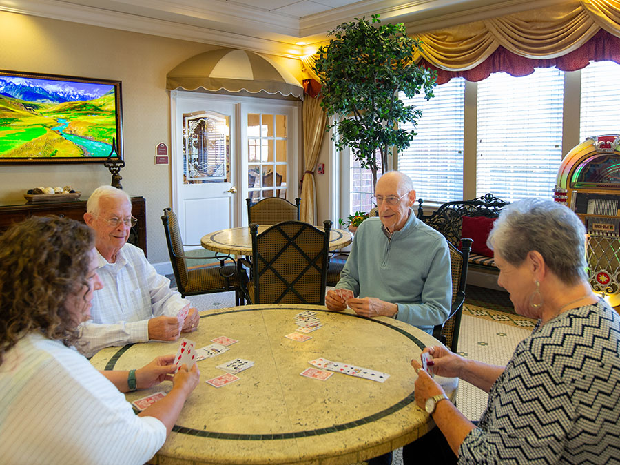 Residents playing cards at table.