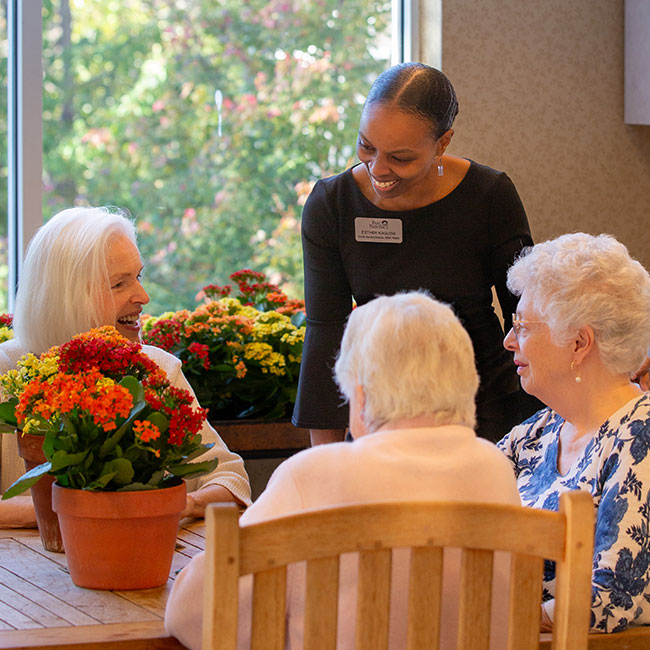 Caregiver speaking with 3 residents at a table.