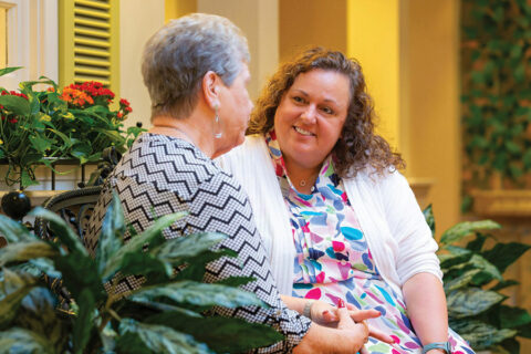 A caregiver sits and speaks with a resident in the village.