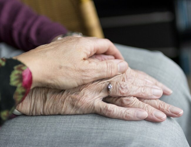 close-up of two people's hands - one comforting the other's.