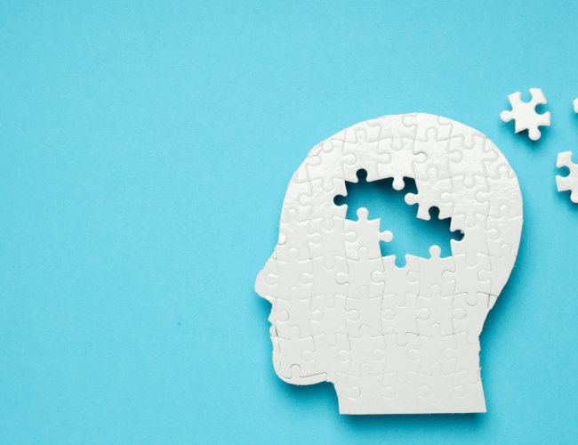 illustration of a white head silhouette as a puzzle with pieces from the brain area pulled out and scattered.